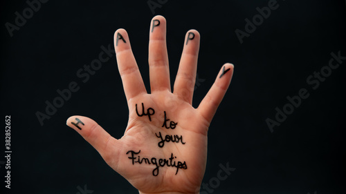 Happy to the tips of the fingers, written on one hand, on a black background	 photo