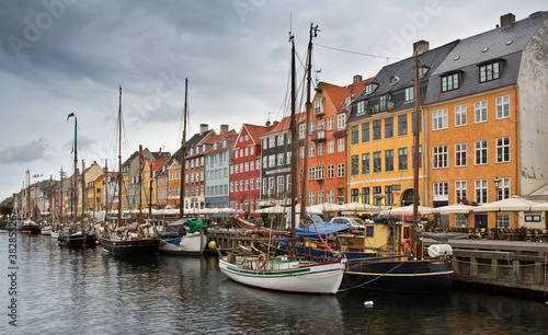 Many boats moored to the dock in the harbor Nyhavn and colorful houses on the embankment against cloudy sky in Copenhagen, Denmark. © Алексей Мараховец