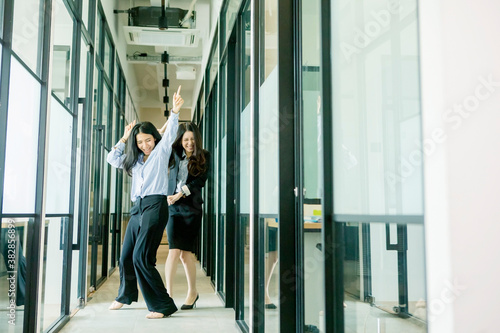 Two happy businesswoman dancing in office corridor
