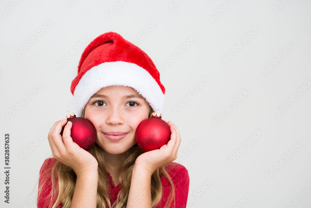 Young girl in red santa hat with christmas balls. Child with Christmas decoration, banner copy space. Isolated on white background. Young girl in red santa hat with christmas balls. Child with Christmas decoration, banner copy space. Isolated on white background.