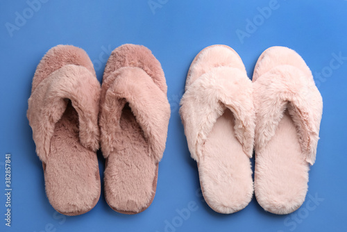 Different stylish soft slippers on blue background, flat lay