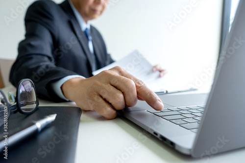 A businessman is pressing a finger on a computer keyboard