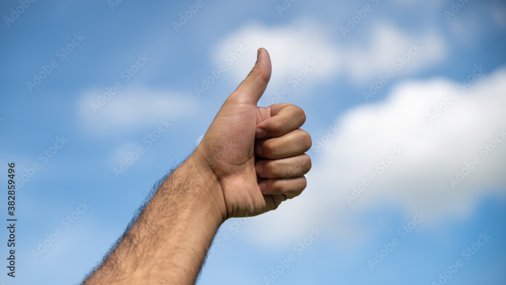 Thumbs up in the blue sky with cotton clouds Thumbs up in the blue sky with cotton clouds