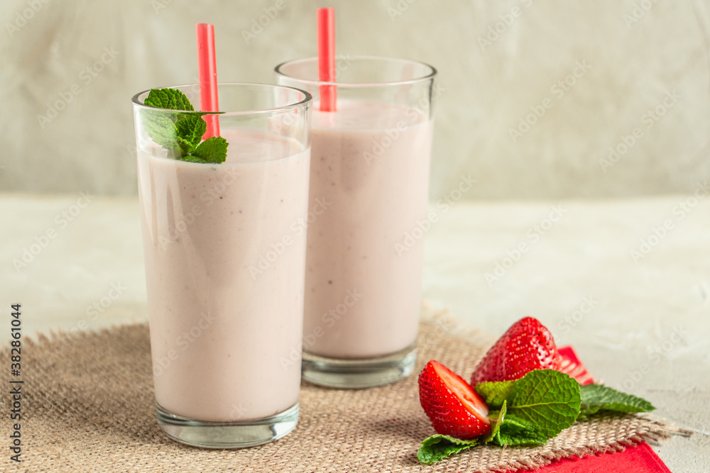 delicious milkshake with strawberries in tall glasses, strawberries and mint, burlap napkin create a cozy atmosphere delicious milkshake with strawberries in tall glasses, strawberries and mint, burlap napkin create a cozy atmosphere