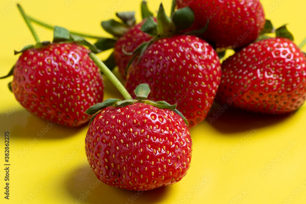side view of juicy ripe strawberries lying on a bright yellow background. Healthy and delicious berries, vegetarian food, healthy food
