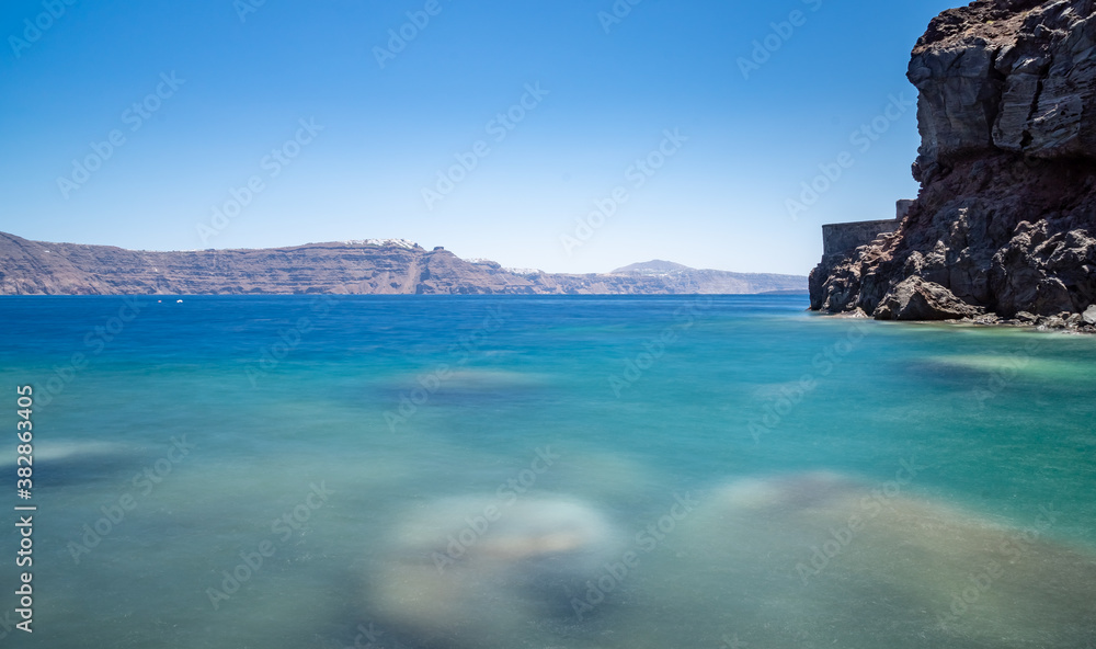view from the beach of the cliff and the Santorini caldera. sunny day, sky without clouds. long exposure shot view from the beach of the cliff and the Santorini caldera. sunny day, sky without clouds. long exposure shot