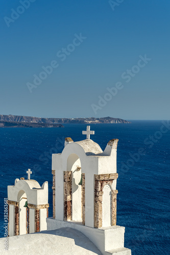 View of Santorini caldera with Oia town and famous old white orthodox church. Portrait format