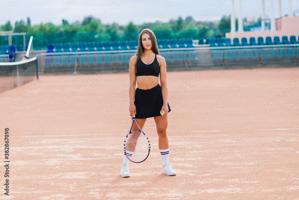 Beautiful stylish sexy woman in black trendy sportswear on tennis court.