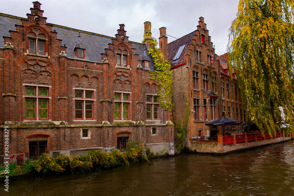 Bruges, Flanders, Belgium, Europe - October 1, 2019. The medieval ancient houses made of old bricks and water channels in the autumn of Bruges (Brugge)