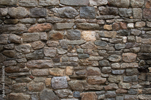 old wall made of multicolored stones sealed with cement