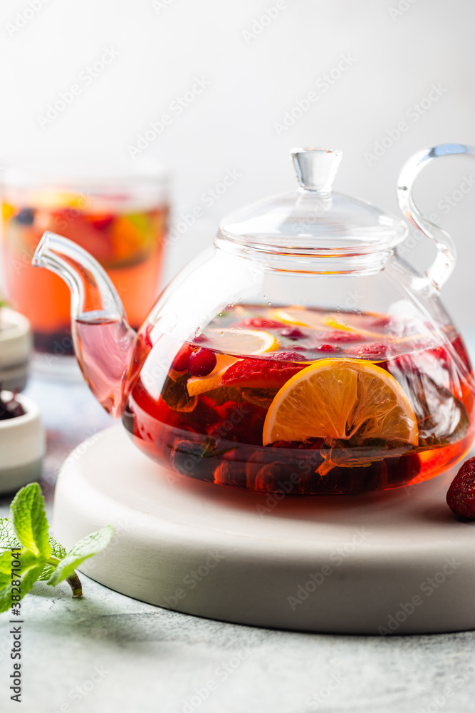 Fruit red tea with berries in glass teapot on white background Fruit red tea with berries in glass teapot on white background