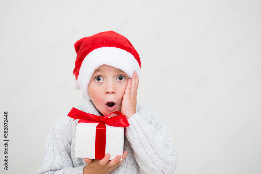 Excited surprised little boy in red santa hat with gift box isolated on white background, banner copy space. Christmas congratulation concept. Excited surprised little boy in red santa hat with gift box isolated on white background, banner copy space. Christmas congratulation concept.