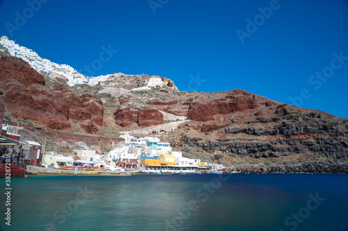 Beautiful panoramic view from the old harbor of Ammoudi under the famous village of Oia on a sunny day. Picturesque natural background. Santorini island, Cyclades, Greece, Europe.