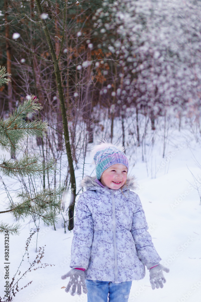 little child playing in snow. sincere joy of the child from playing in the fresh air. raising immunity in winter. playing snowballs in the winter forest little child playing in snow. sincere joy of the child from playing in the fresh air. raising immunity in winter. playing snowballs in the winter forest