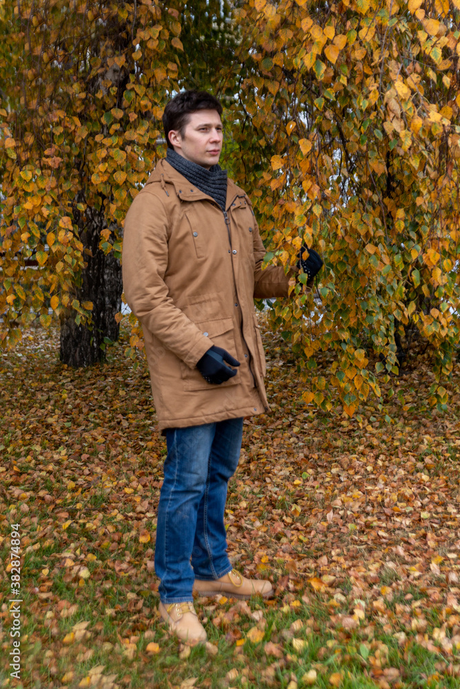 A young white man on an autumn walk in the park in casual clothes. A young white man on an autumn walk in the park in casual clothes.
