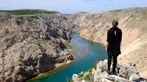 Girl in a black dress enjoying the breathtaking view of the Zrmanja canyon in Croatia. Sense of freedom travelling in Europe on the top of the canyon overlooking still turquoise water. photo