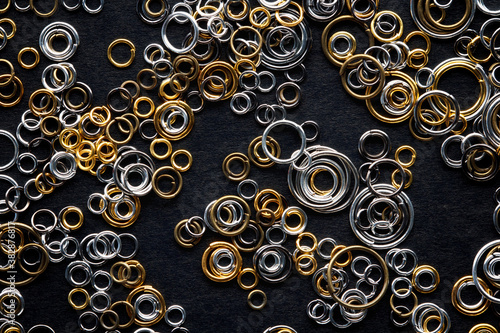 round metal links, accessories for jewelry making, scattered on a black background