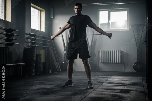 Sportive Man Stretch His Arms With Skipping Rope .