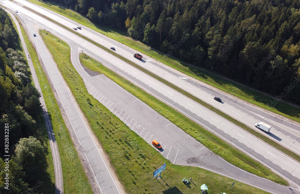 Top view of the long highway autobahn with cars through the forest