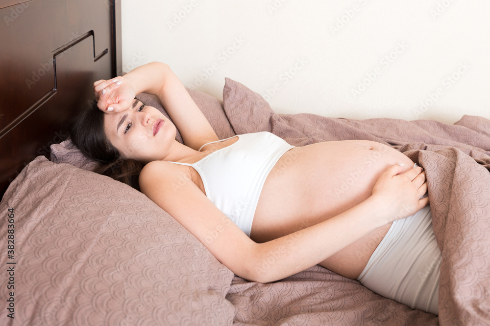 Obraz premium beautiful young pregnant woman lying in bed, top view. the girl suffers from the fact that her husband left her