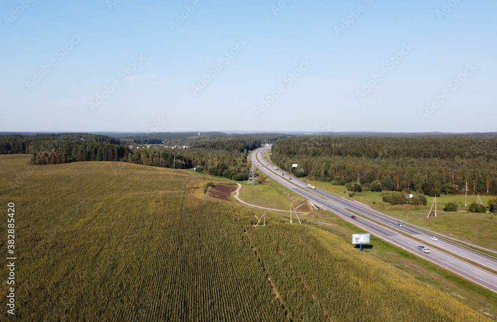 Fototapeta premium Top view of car asphalt highway with cars through fields