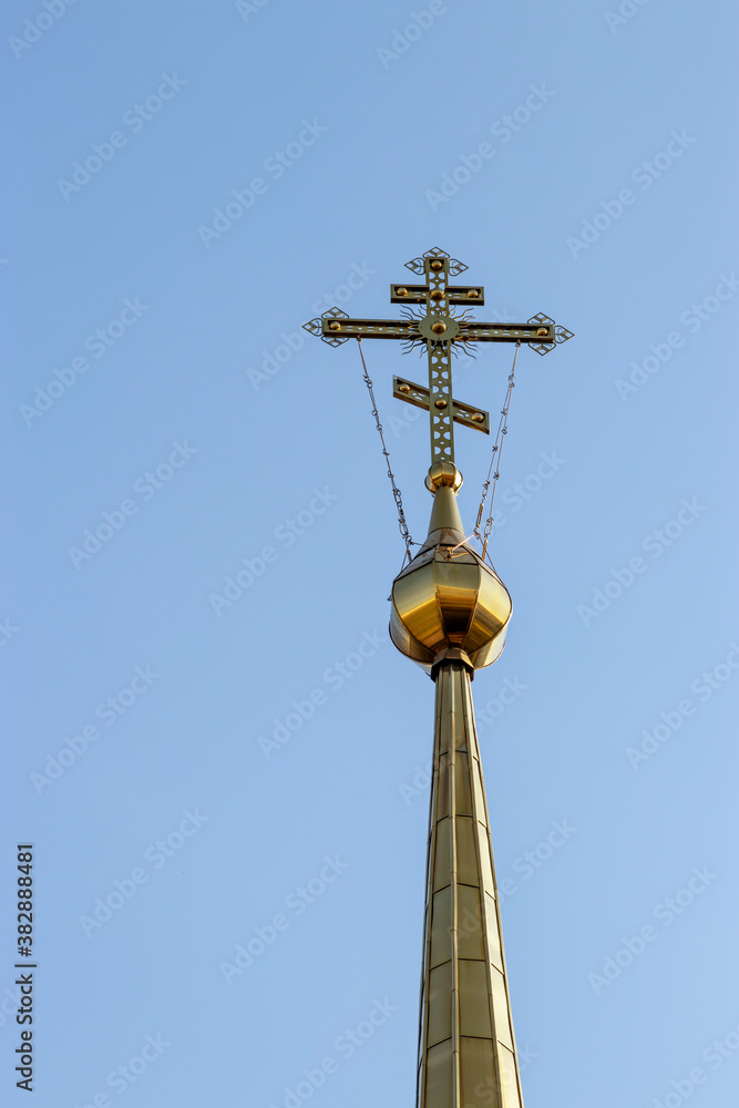 Beautiful gold cross of the Christian Russian church against the blue sky. Religion and culture of Russia.