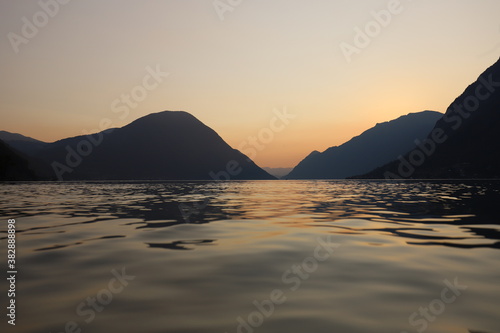 Colorful sunset in Italy over a mountain range with still lake in foreground during golden hour in late summer
