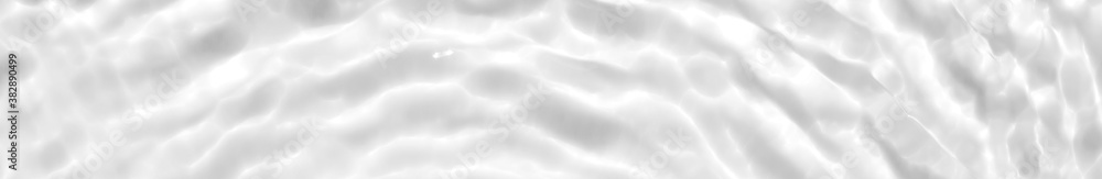 Fototapeta premium Photo of water waves shadow. Subtle white texture of light-shadow pattern of sunlight reflection from rippled water surface. Beautiful natural wallpaper. White-grey water waves marbling.