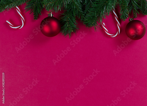 Merry Christmas and happy New Year red background with evergreen branches plus ball ornaments and candy canes