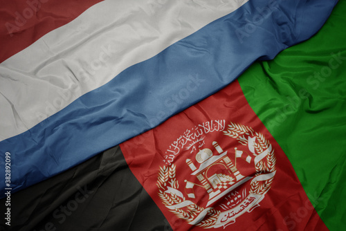 waving colorful flag of afghanistan and national flag of luxembourg. macro
