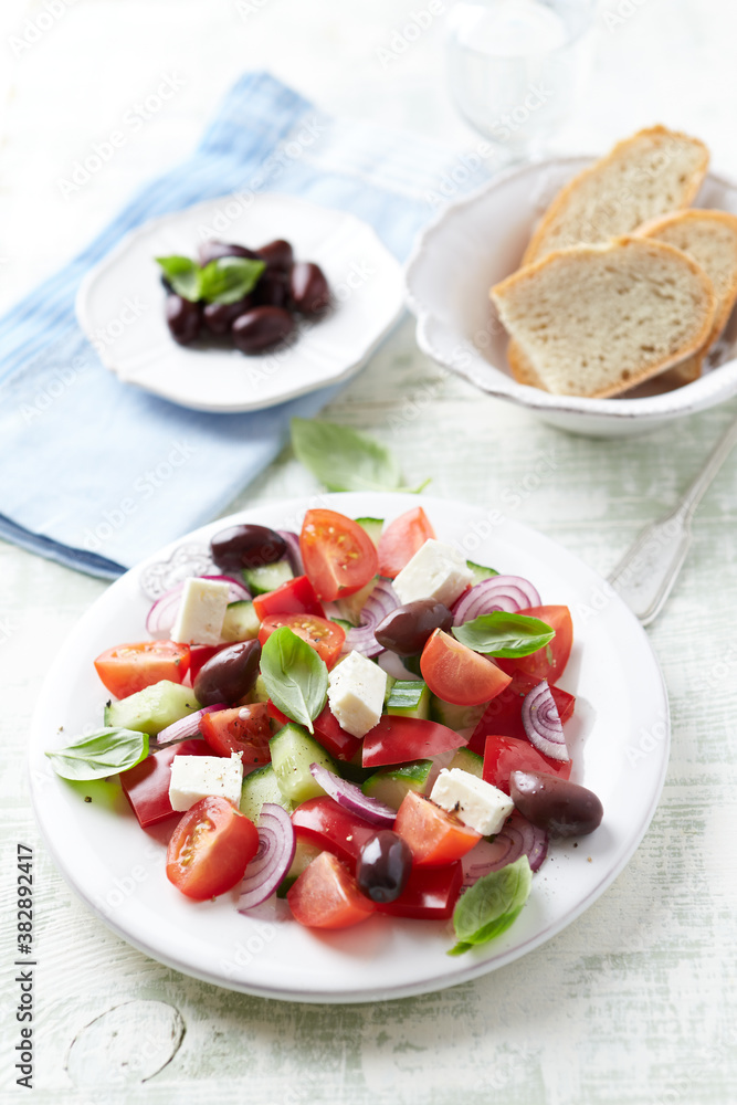 Simple salad with cherry tomatoes, feta cheese, kalamata olives, red pepper and fresh herbs. Bright wooden background. Close up.	