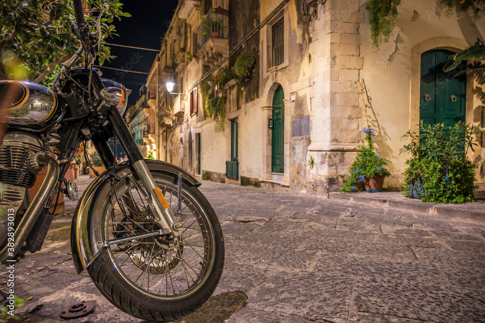 Klassisches Motorrad parkt in der Altstadt Ortygia in schöner Gasse bei Nacht