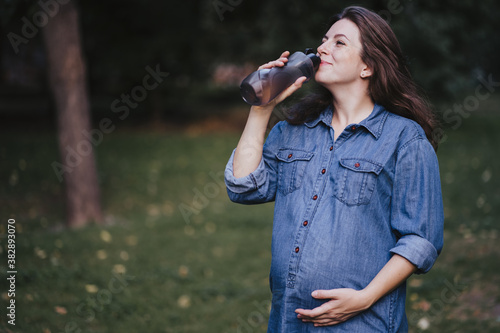 Pregnant woman drinking water during outdoor walk