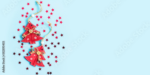 Wooden Christmas toys in the form of red Christmas trees and confetti in the form of Christmas trees and stars on a blue background. Christmas, New year. The view from the top, place for text