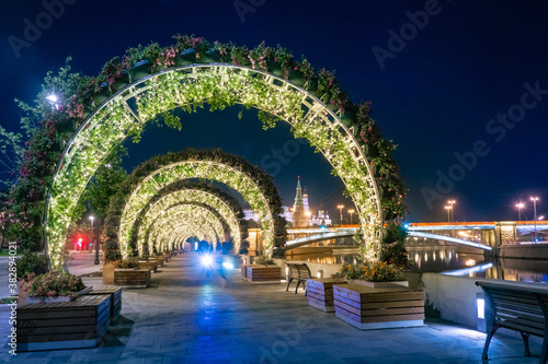 Evening in Moscow. Decorations of the Russian capital. Arches of plants on the embankment of the Moscow river. Zaryadye Park. Illuminated arches on the background of Moscow attractions.