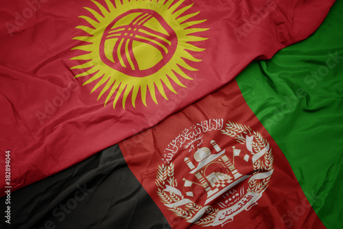 waving colorful flag of afghanistan and national flag of kyrgyzstan. macro