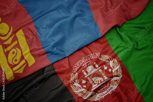 waving colorful flag of afghanistan and national flag of mongolia. macro