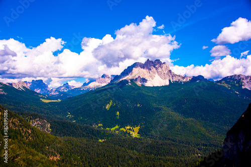 pine forests and pink dolomites among white clouds