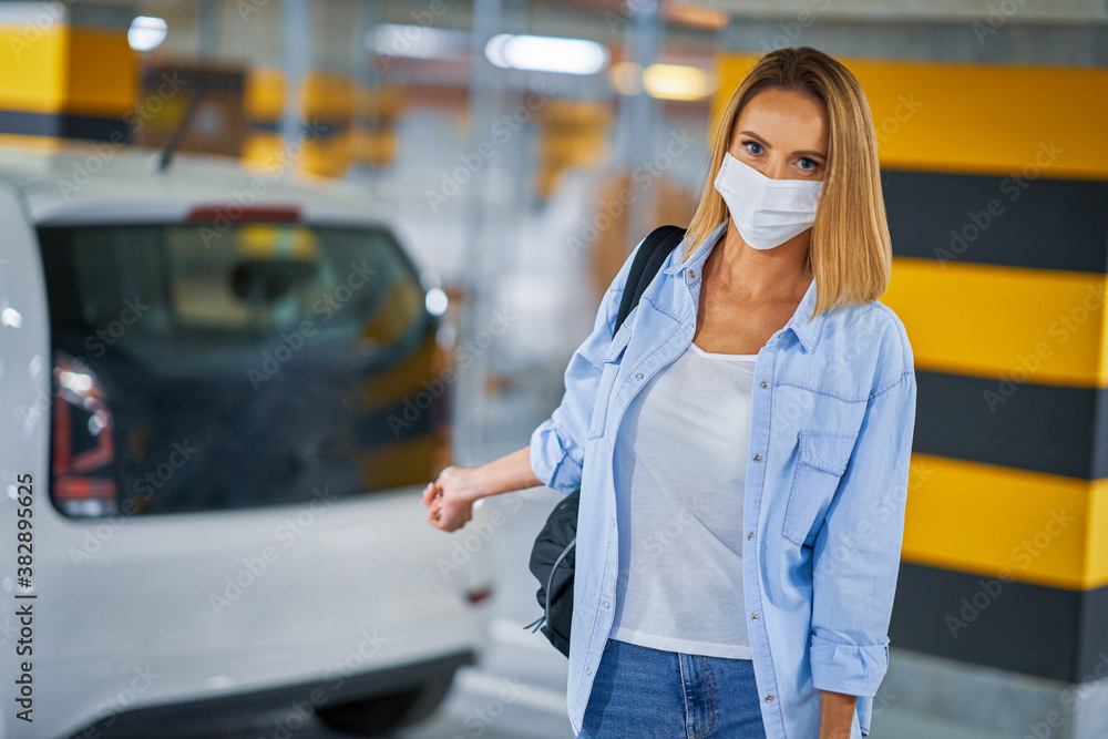 Fototapeta premium Student in mask leaving car in underground parking lot