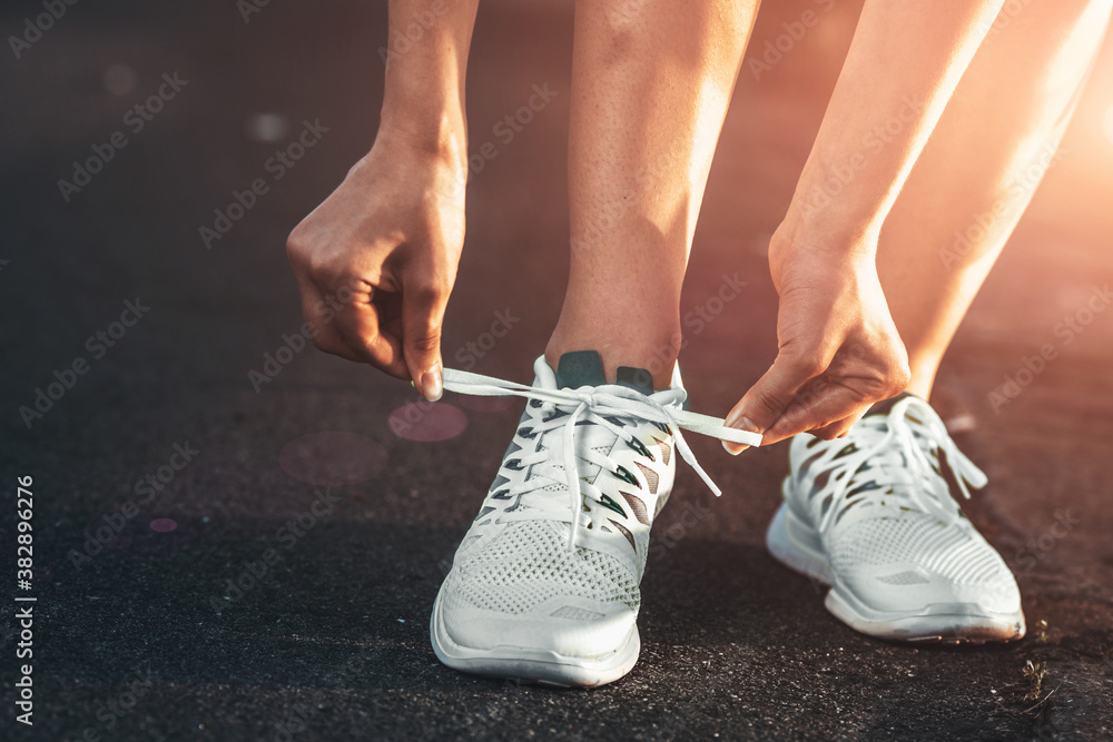 Running shoes. Barefoot running shoes closeup. Female athlete tying laces for jogging on road in minimalistic barefoot running shoes. Runner getting ready for training. Sport lifestyle.