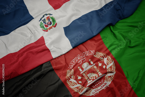 waving colorful flag of afghanistan and national flag of dominican republic. macro