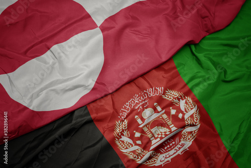 waving colorful flag of afghanistan and national flag of greenland. macro