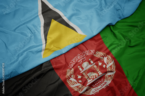 waving colorful flag of afghanistan and national flag of saint lucia. macro