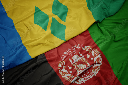 waving colorful flag of afghanistan and national flag of saint vincent and the grenadines. macro
