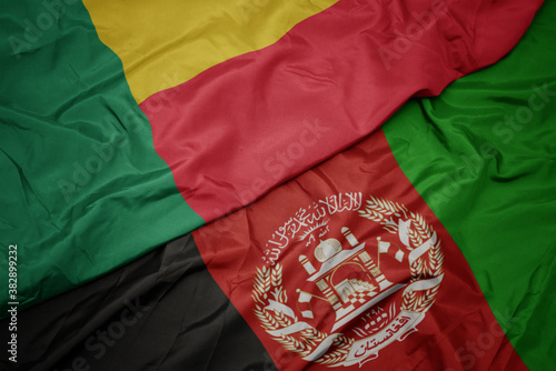 waving colorful flag of afghanistan and national flag of benin. macro