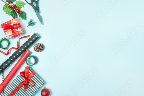 Obraz na płótnie Gift boxes wrapped in black and white striped and red paper with wrapping materials over a blue background. Christmas presents preparation. Copy space. w salonie