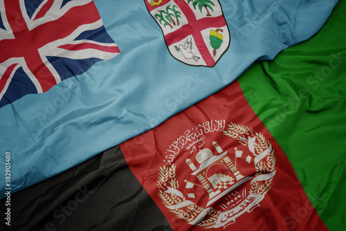waving colorful flag of afghanistan and national flag of Fiji . macro