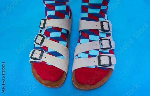 aerial view of the feet in sandals and colored socks on a blue background photo