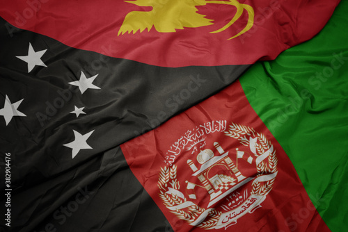 waving colorful flag of afghanistan and national flag of Papua New Guinea . macro