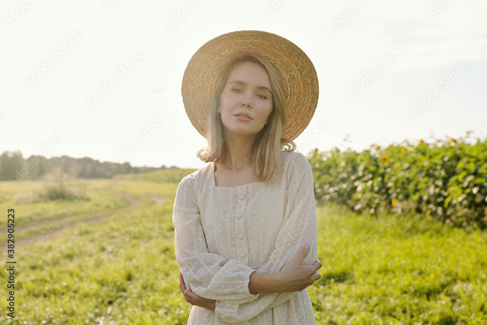 Gorgeous young blond woman in straw hat and white country style dress